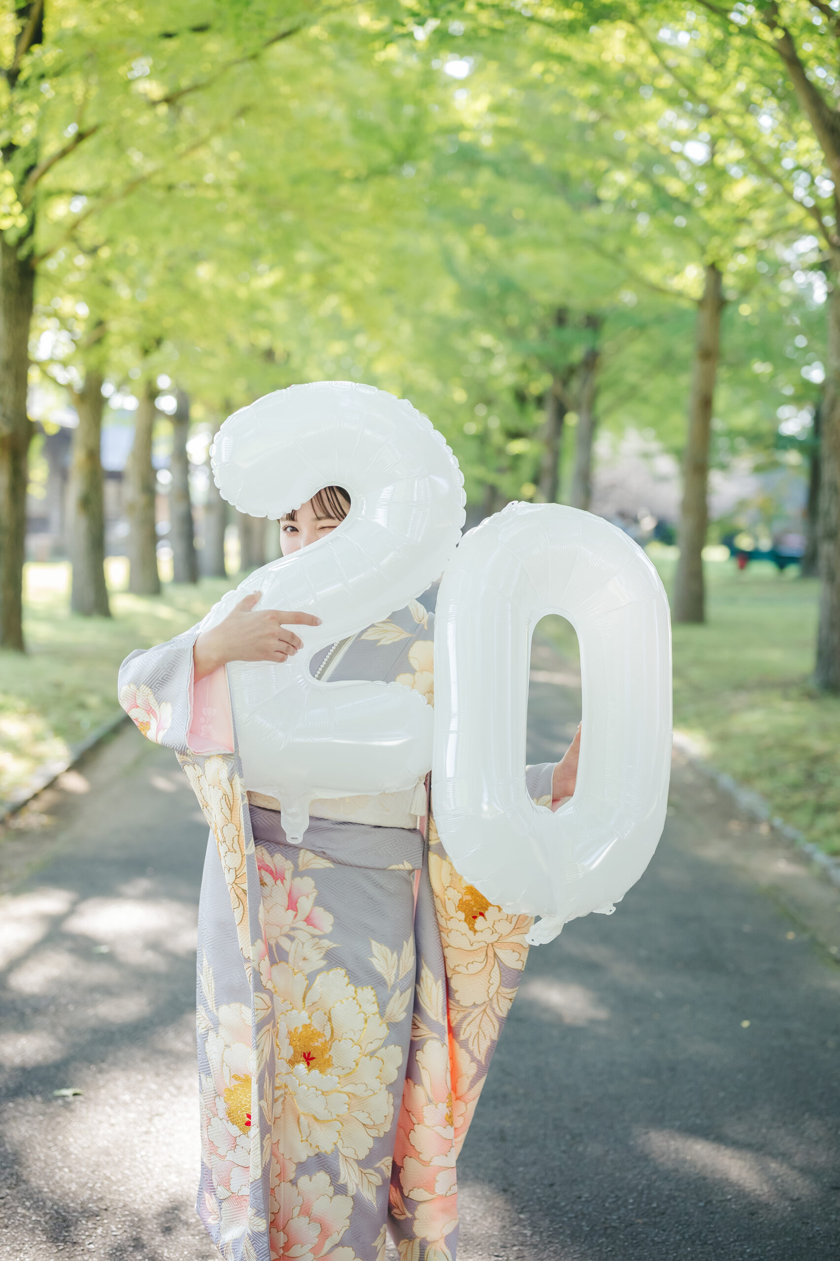 水戸の美しい新緑の並木道をバックに20歳のナンバーバルーンを持ってポーズを決める可愛い成人式前撮り
