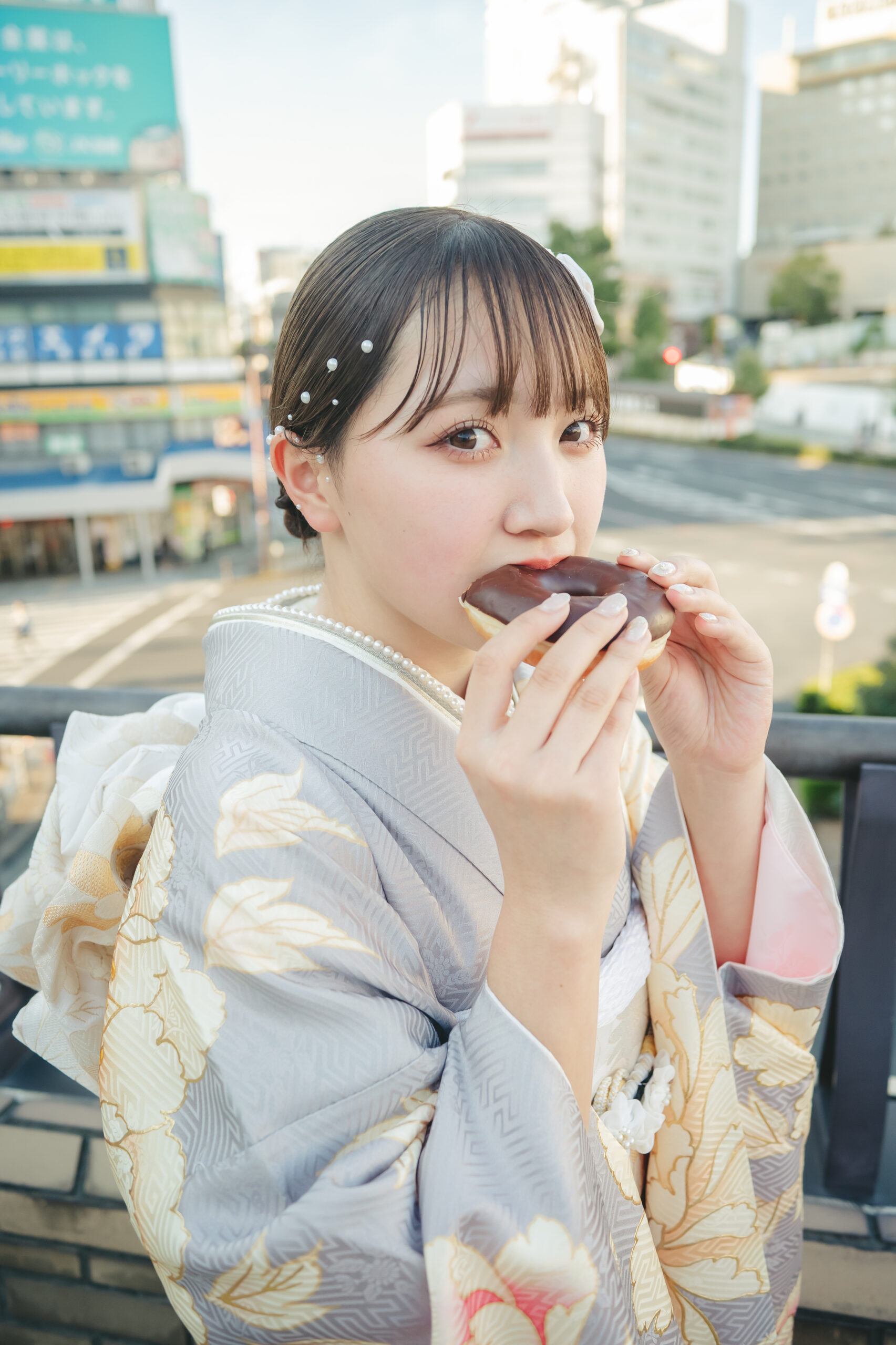 水戸の街並みをバックに振袖姿でドーナツを美味しそうに頬張る可愛すぎる成人式前撮りのオフショット