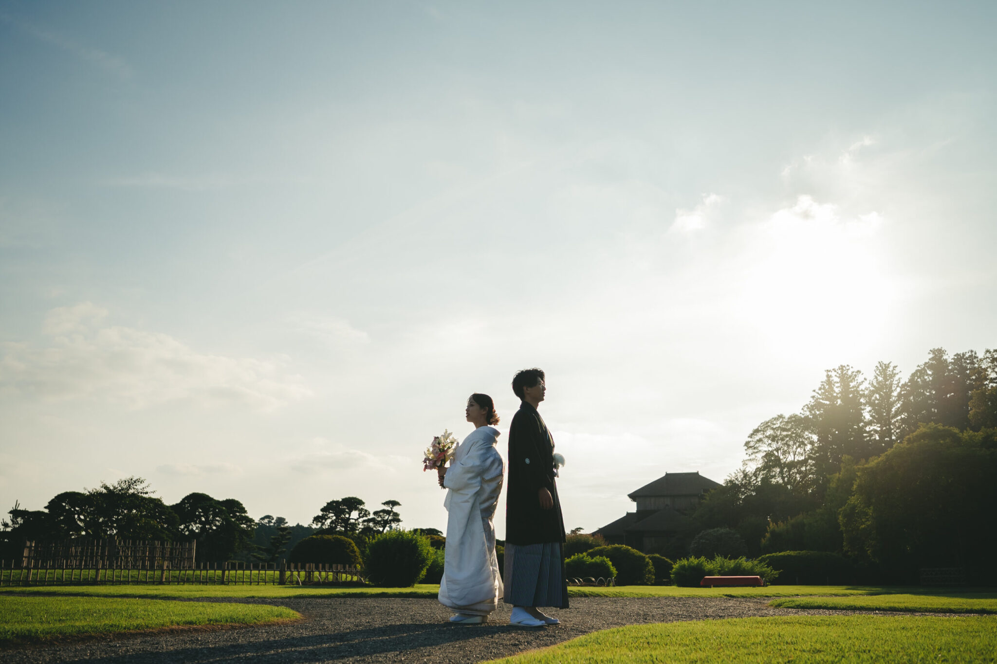 偕楽園の広大な庭園に差し込むドラマチックな夕日と木漏れ日に包まれた新郎新婦のシルエット