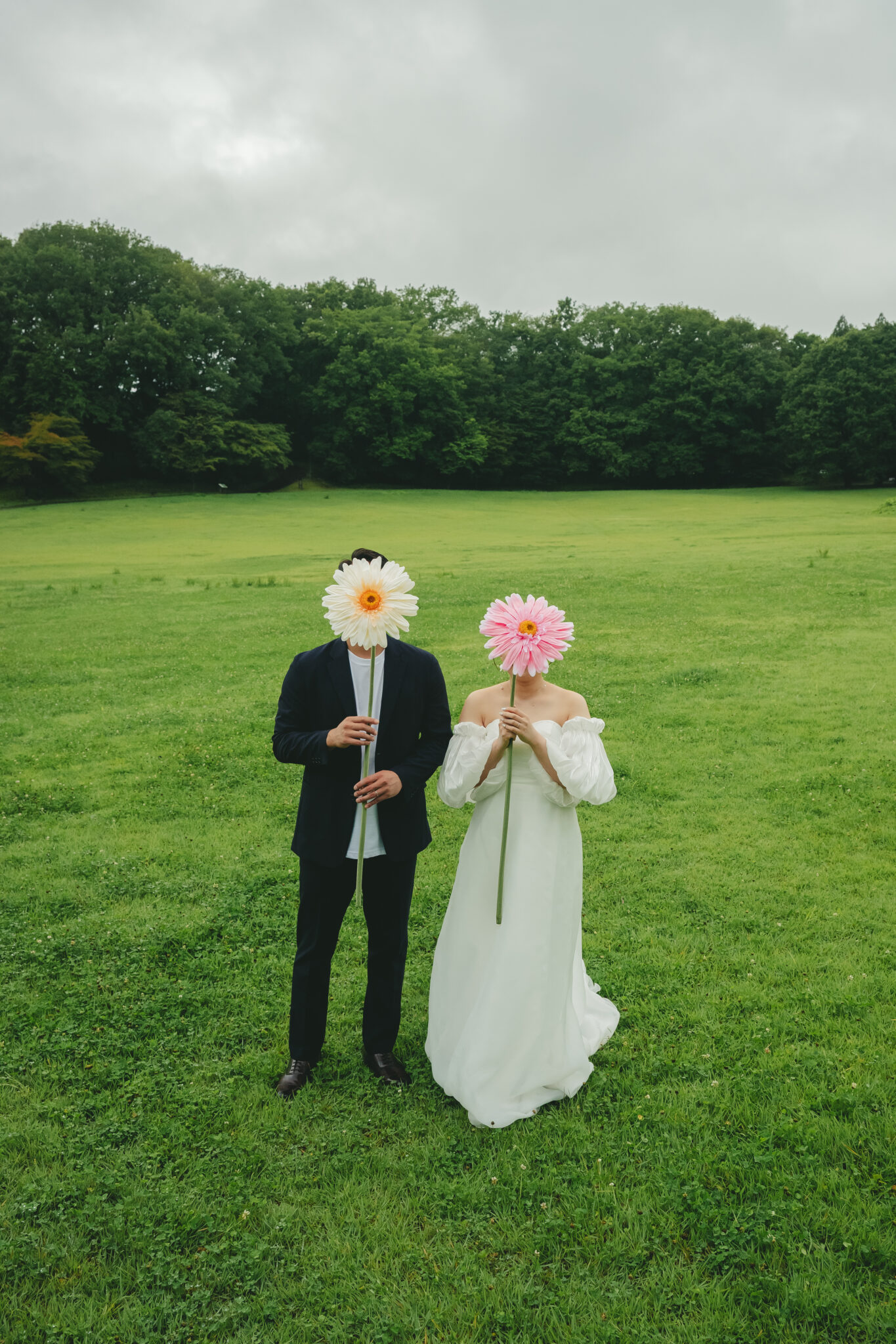 うつのみや文化の森の広い芝生で大きなお花のプロップスを持って笑顔の2人のナチュラル前撮り
