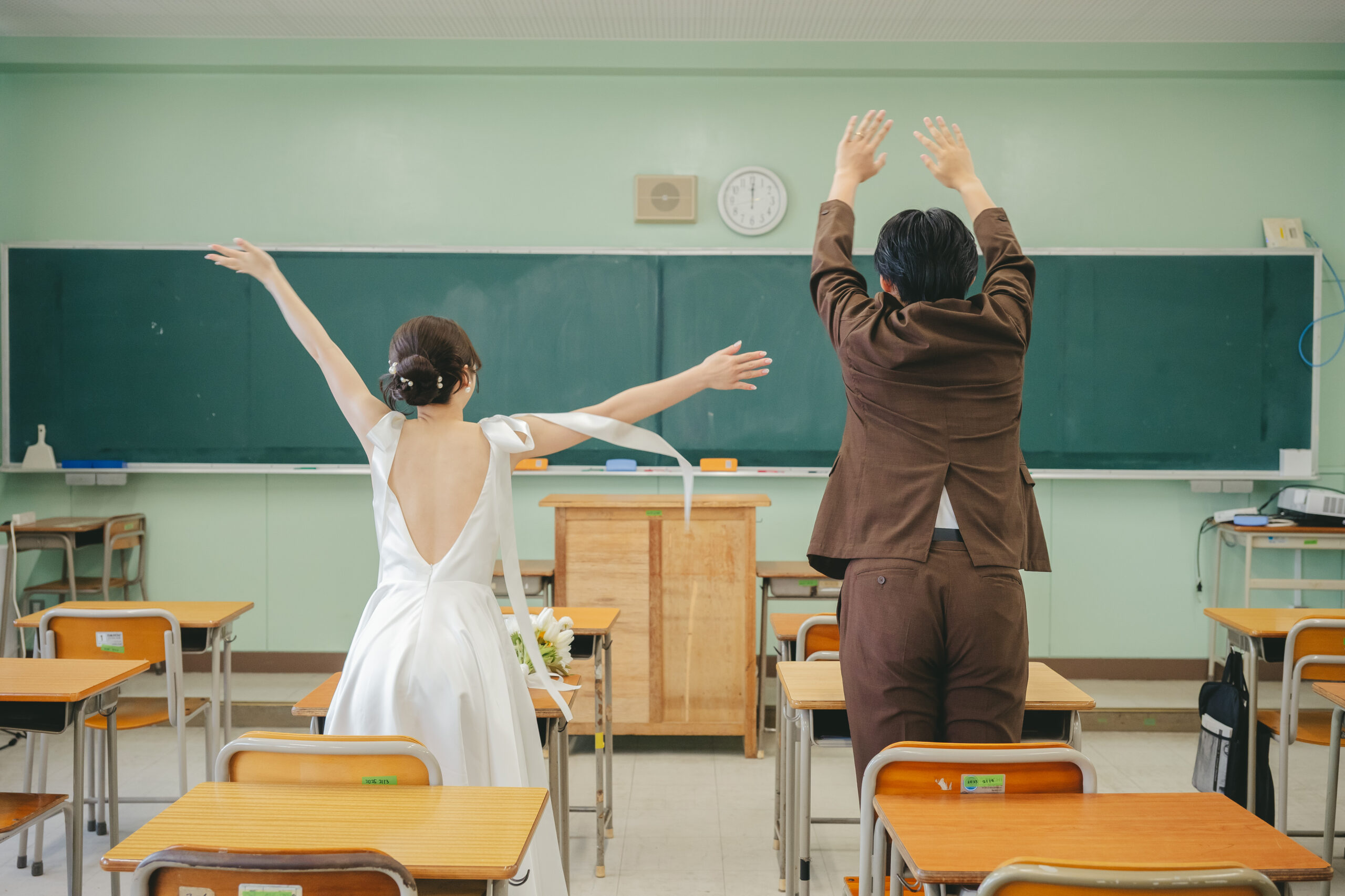 教室の大きな黒板に向かって二人で手と足を挙げるお茶目で可愛い学校前撮り