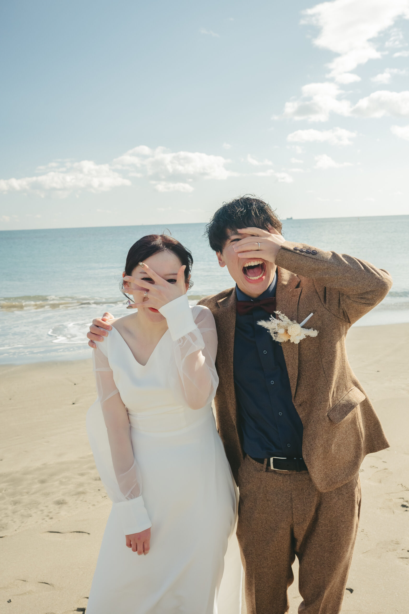 菖蒲田浜海水浴場の青空の下で笑顔でいるウェディングドレスの二人
