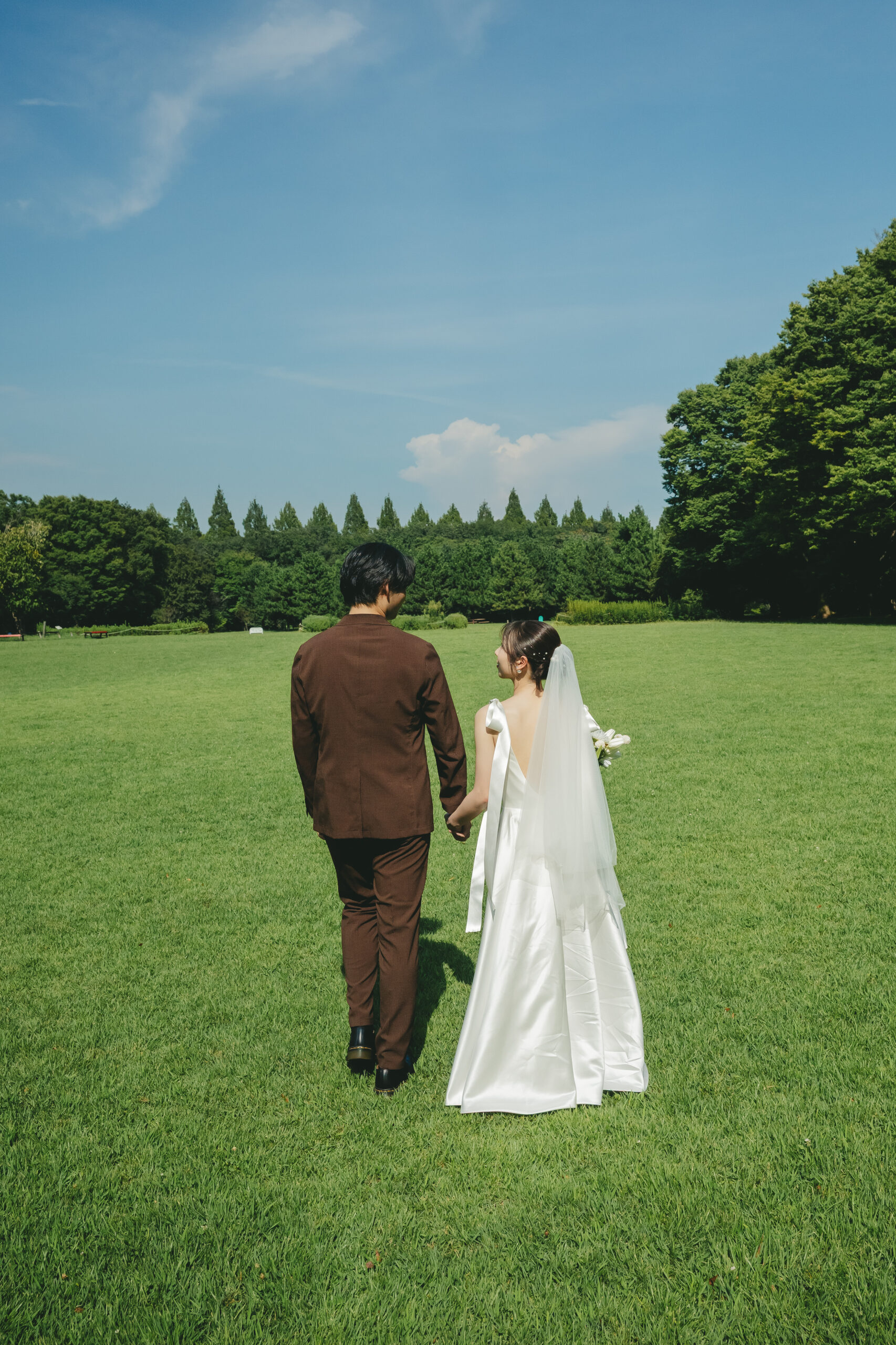 県立相模原公園の広大な芝生と青空の下で手を繋いで歩くナチュラルな結婚式前撮り