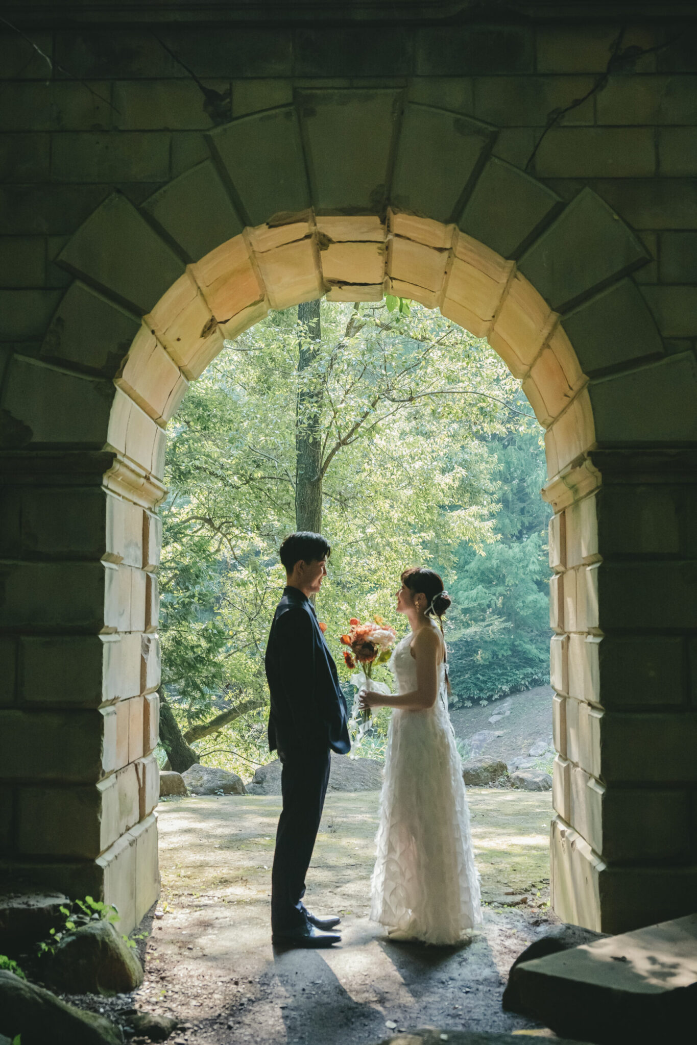 七ツ洞公園を象徴する英国風の石造りアーチの中でドラマチックに向き合う新郎新婦のウェディングフォト