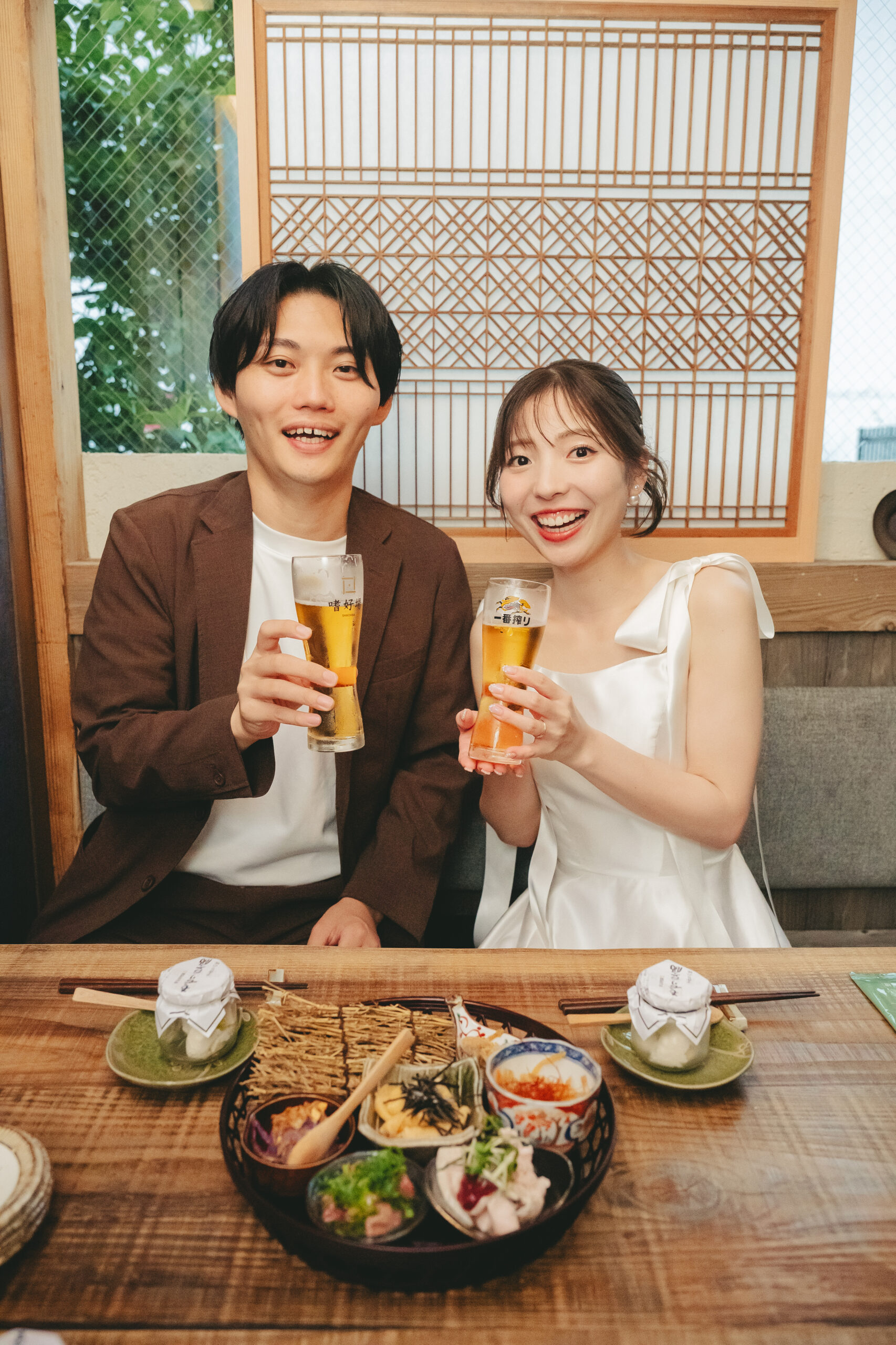 居酒屋でビールをの新郎新婦。居酒屋で結婚式前撮り