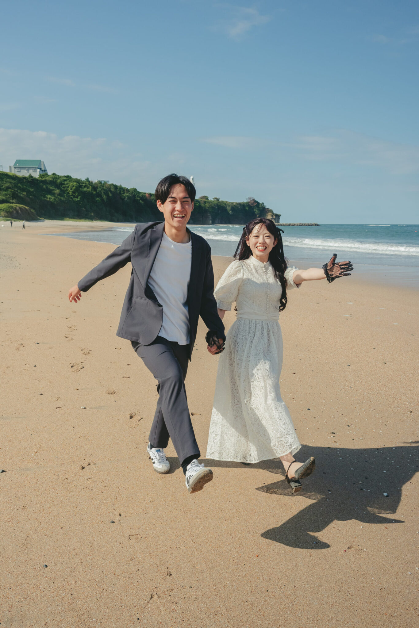 久慈浜海水浴場の綺麗な砂浜の上をドレスとカジュアルなスーツ姿で笑顔で駆け抜ける前撮り