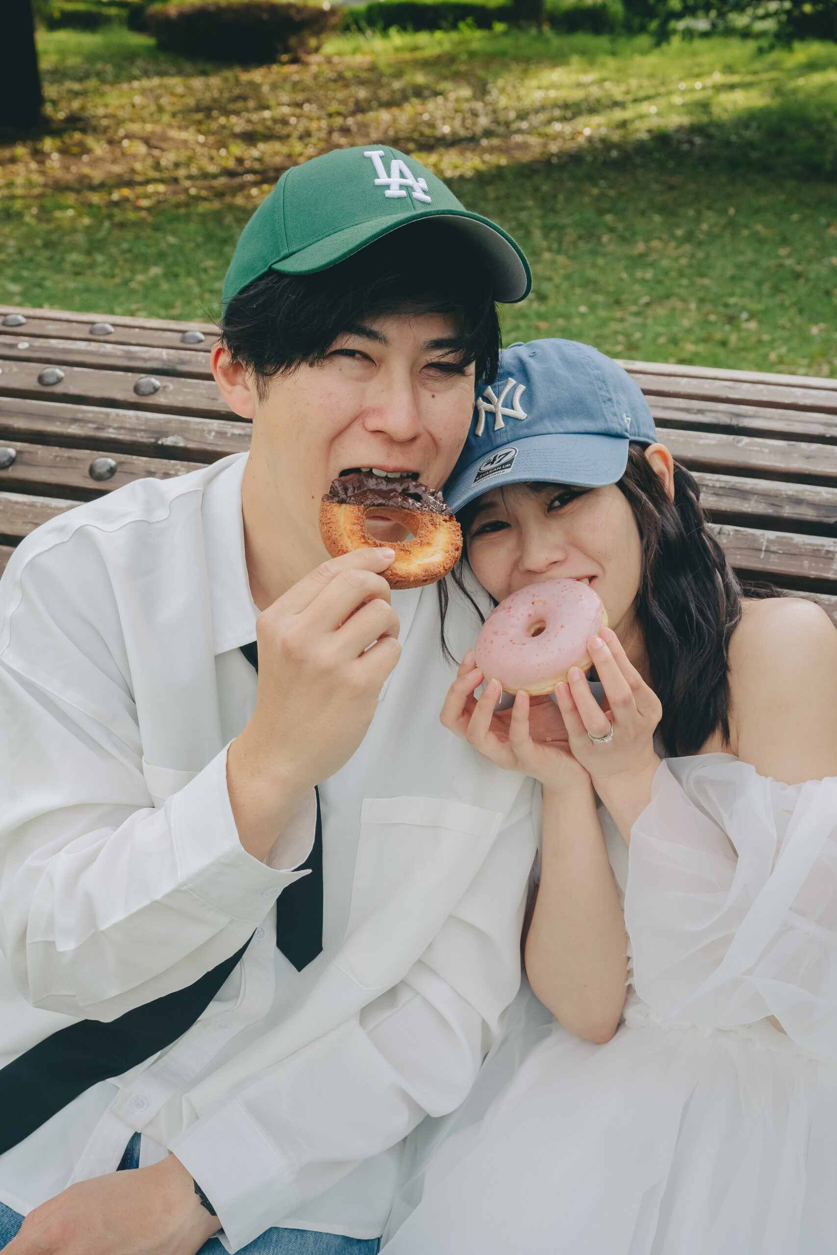 公園のベンチに座ってドーナツを美味しそうに頬張る可愛すぎるカジュアルウエディングフォト