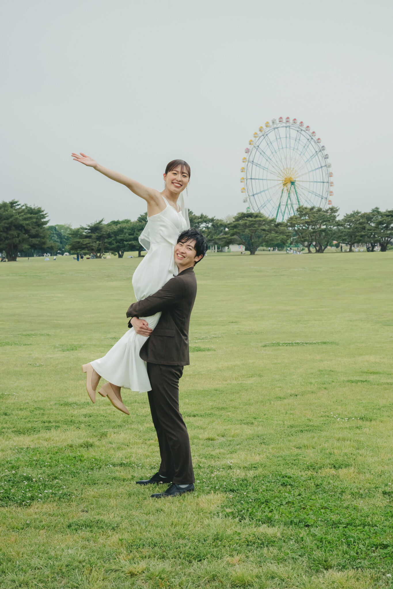 ひたちなか海浜公園の観覧車と広い芝生をバックに新婦を優しく抱き上げるロケーション前撮り