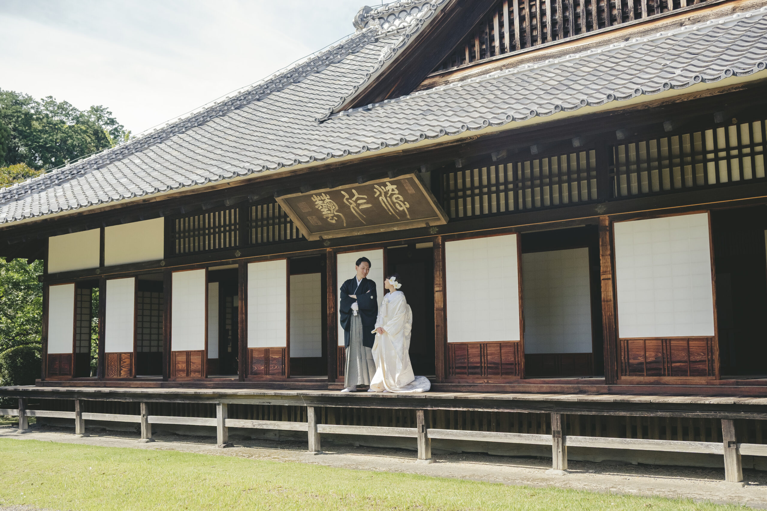 弘道館の壮大な木造建築と縁側を背景に凛とした立ち姿を見せる和装の結婚式前撮り