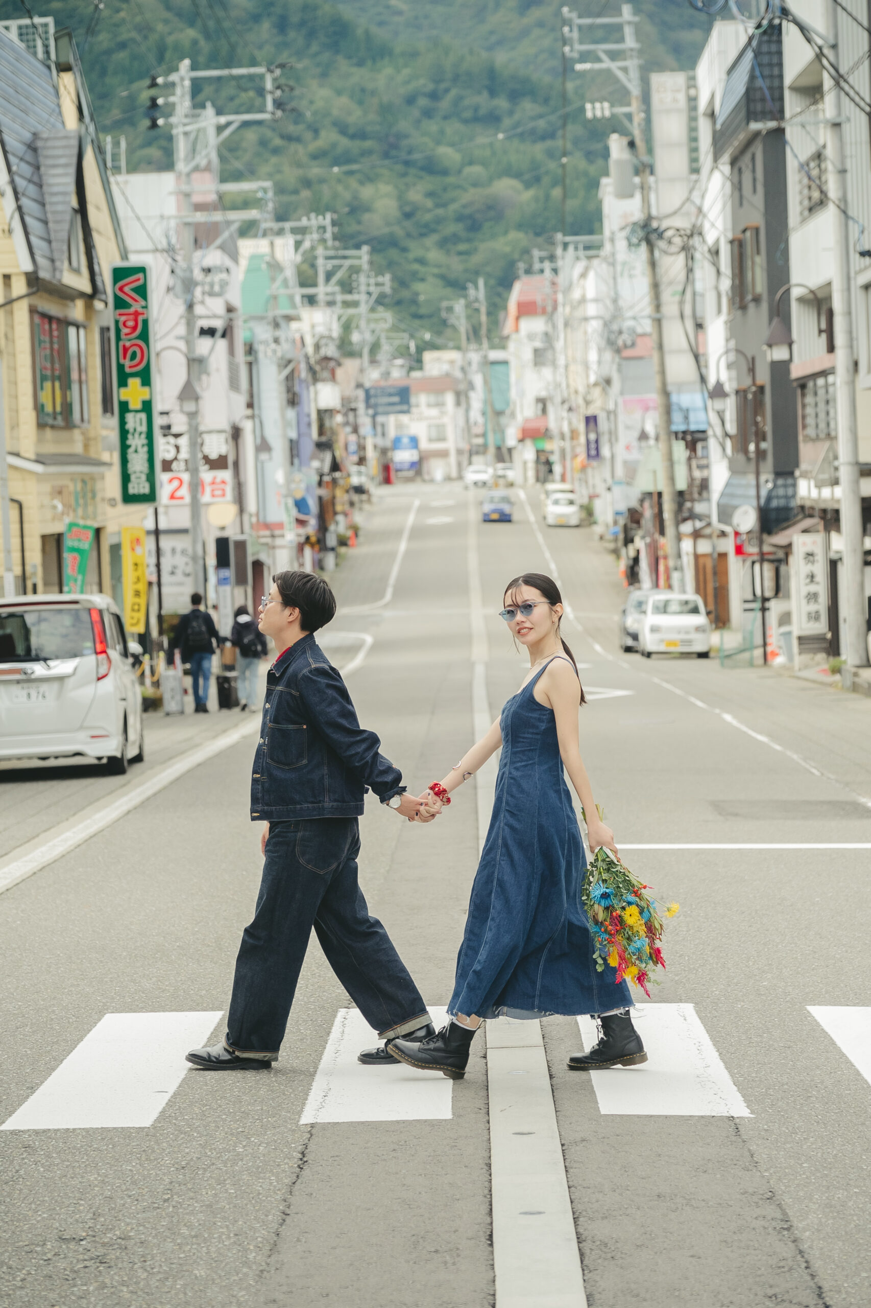 新潟県越後湯沢の温泉街の横断歩道をデニムコーデで手をつないで渡る前撮りカップル