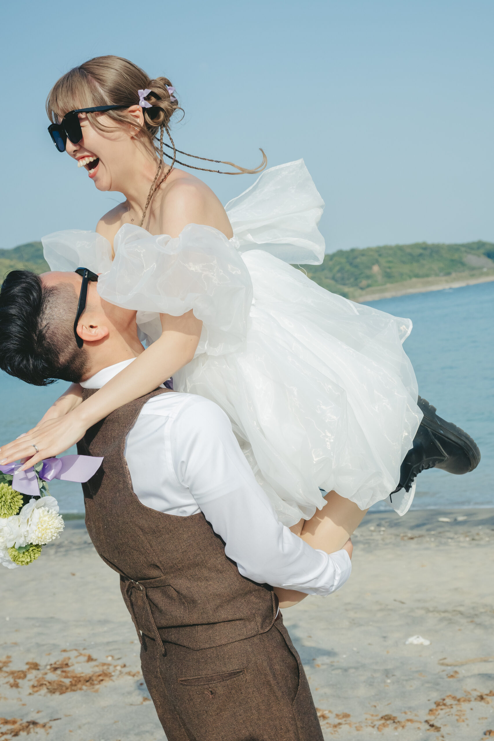 志布志の砂浜でミニドレス姿の新婦を抱っこする新郎