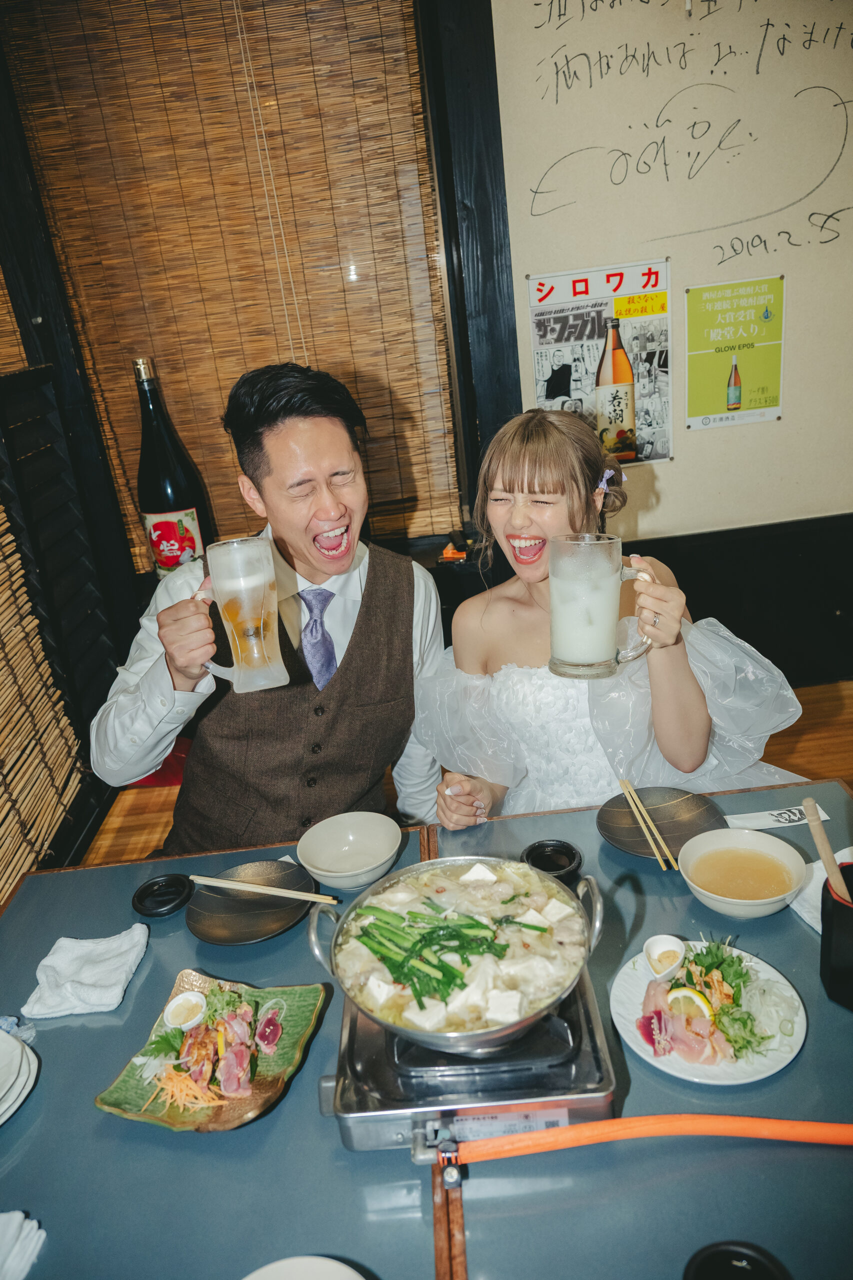 鹿児島の居酒屋心菜坊でグラスを持って笑顔で乾杯する前撮りの二人